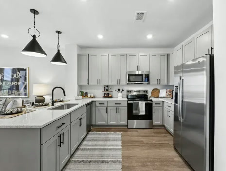 Encore Brentwood apartment kitchen with grey shaker cabinets and quartz countertops